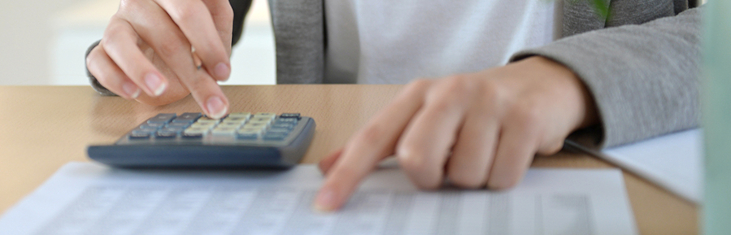 Hände auf dem Tisch, Berechnung mit dem Taschenrechner